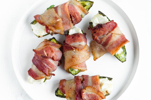 spicy bacon wrapped cream cheese poppers on a plate with a toothpick