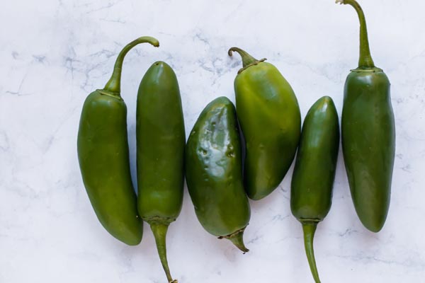 a bunch of raw jalapenos on a cuttings board