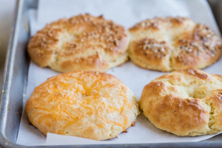 four bagels of different flavors on a baking tray