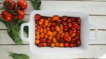 tomatoes tossed in olive oil in a white casserole dish