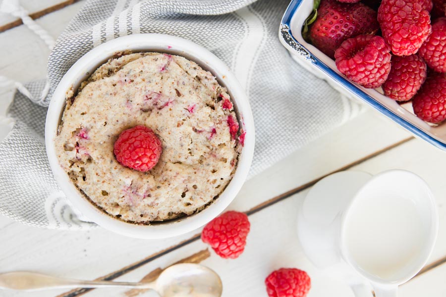 baked oatmeal next to a container of raspberries and cream