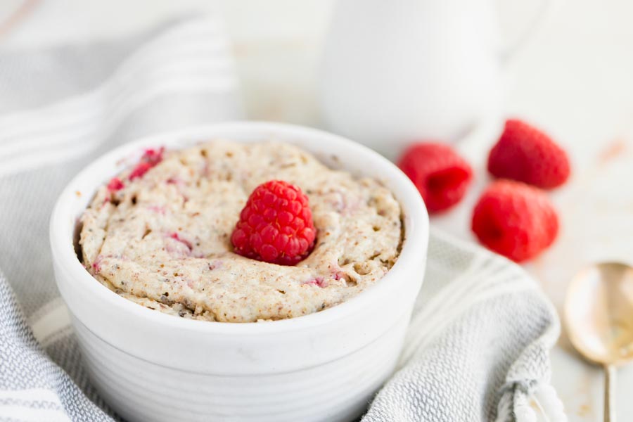 baked oats in a small bowl topped with a raspberry