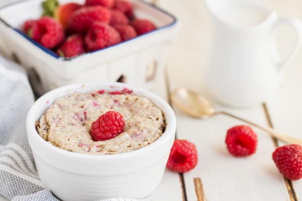 baked oatmeal in a white ramekin with raspberries around