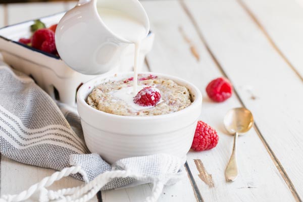 pouring cream on top of a small bowl of oatmeal