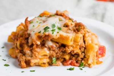 Baked ziti pasta with ground beef and cheese on a plate.