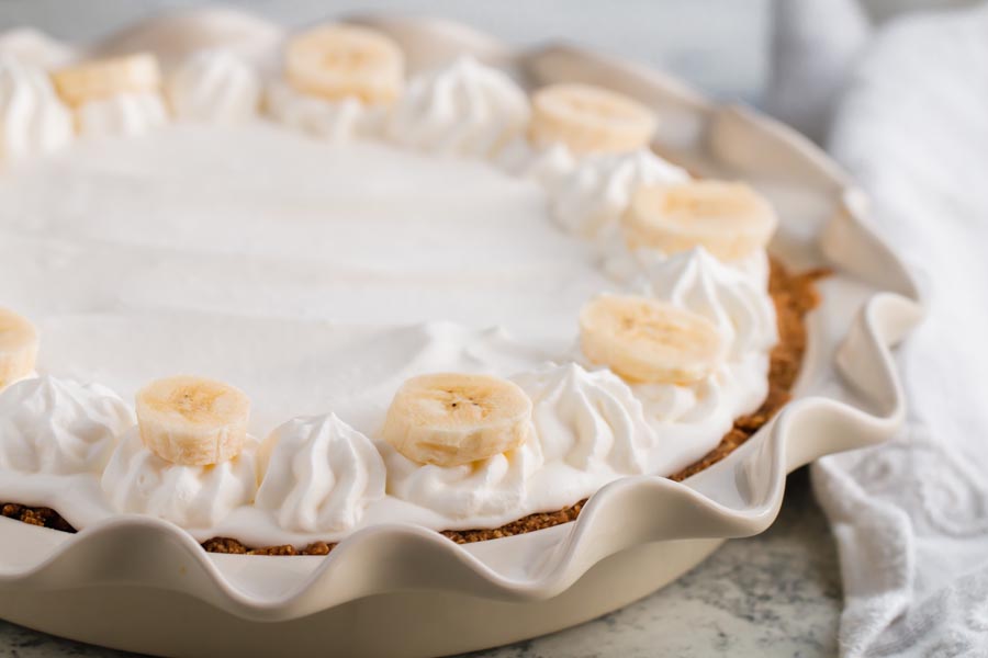 banana cream pie decorated with whipped cream and bananas