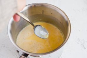a saucepan with keto custard inside and a spoon coated with the custard