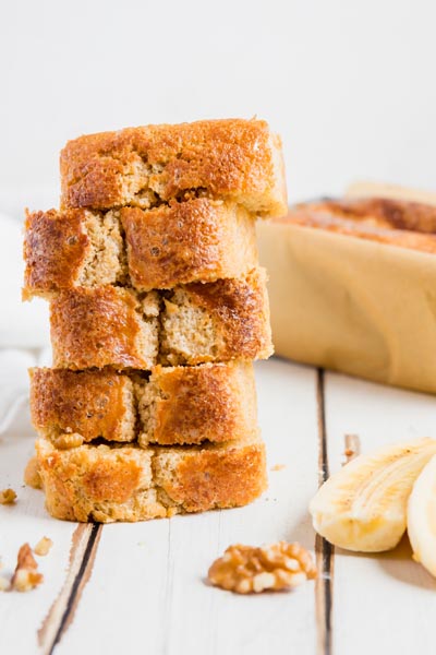 a stack of banana bread slices on a white board with sliced banana nearby