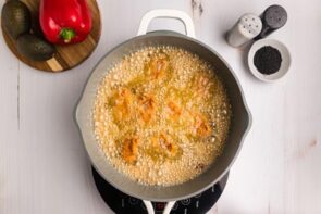 A skillet with breaded chicken frying inside.