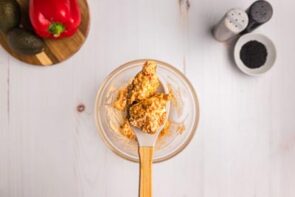 A spoon holding fried chicken covered in bang bang sauce.