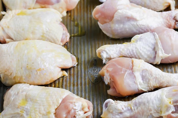 raw pieces of chicken on a baking tray