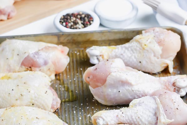 chicken on a baking tray seasoned with salt and pepper