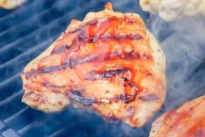 brushing bbq sauce on a chicken thigh