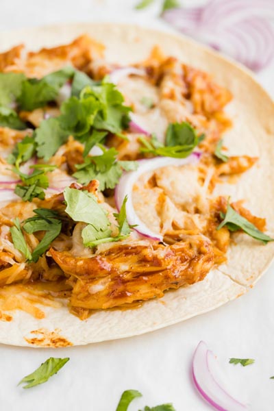 tostada topped with bbq chicken, cilantro and red onion