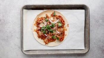 a baked tostada topped with cilantro leaves