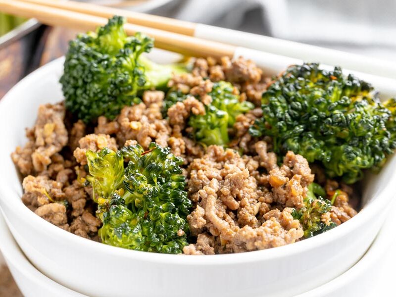 a bowl of broccoli beef with chopsticks near