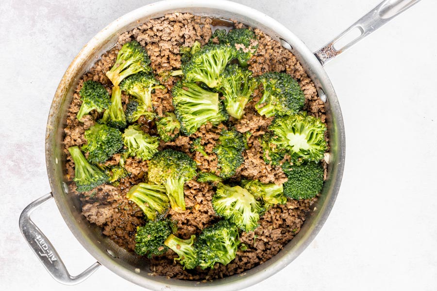 a skillet with beef and broccoli inside