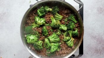 steak broccoli scattered around a skillet with cooked ground beef