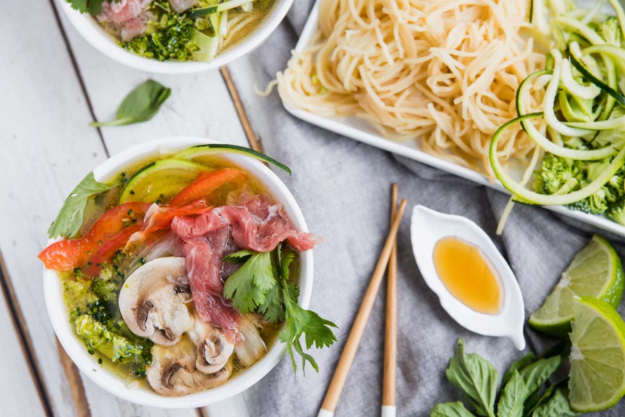 two bowls of pho with a little bit of sauce sauce in a bowl and noodles near