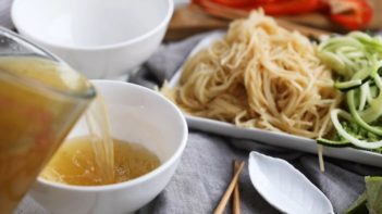 pouring pho broth into a small white bowl