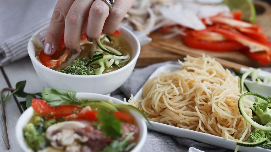 placing broccoli and zucchini noodles in some broth