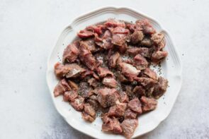 A plate with stew meat on it seasoned with salt and pepper.