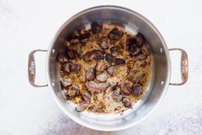 A stock pot with stew meat seared on the bottom.