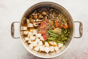 Diced daikon radish, green beans, carrot and mushroom inside a large stock pot.