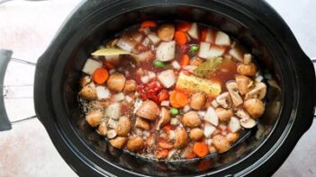 A crockpot with beef stew cooking inside.