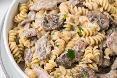 Close-up of keto beef stroganoff with steak, mushrooms, and rotini pasta coated in a rich sour cream sauce.