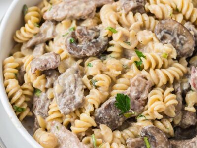 Close-up of keto beef stroganoff with steak, mushrooms, and rotini pasta coated in a rich sour cream sauce.
