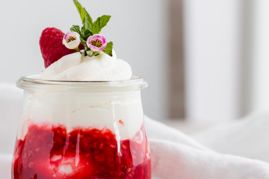 layers of berry syrup and whipped cream in a glass jar