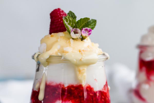 close up of melted white chocolate dripping from sugar free raspberry fool with mint leaf on top