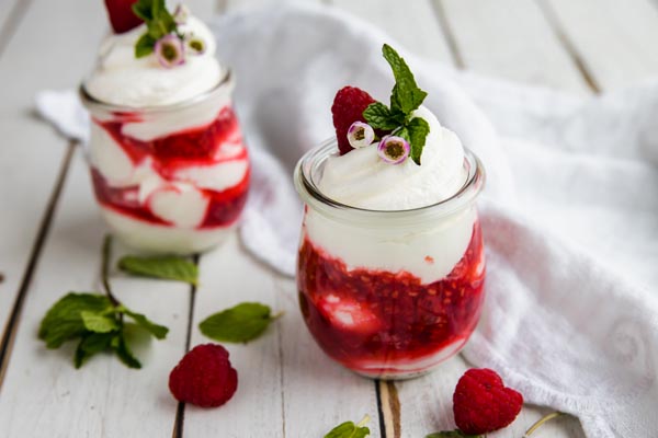 two berry whipped desserts called fools on a table with a white napkin