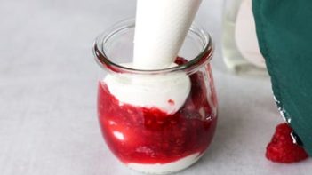piping keto whipped cream into a jar with raspberry syrup