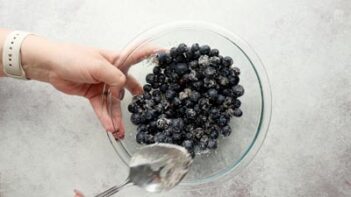 stirring blueberries and sweetener with a spoon