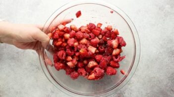 holding a bowl of mixed raspberries and diced strawberries