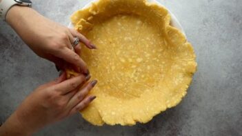 pressing pie crust into a pie plate with hands