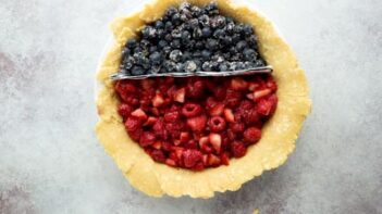 two sides of a pie separated by foil, blueberries are on one side and red berries in the other