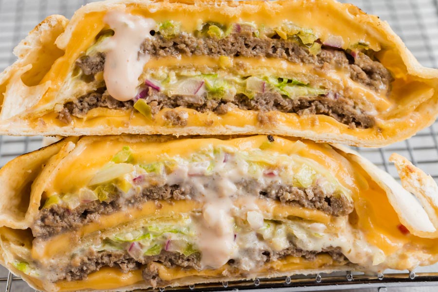 Closeup of a cheesy, beefy Big Mac wrap with special sauce dripping down from the wrap.