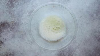 Frothed egg whites sitting in a clear glass bowl, ready to be mixed with the wet ingredients.