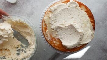 A layer of keto white cake being frosted with creamy vanilla buttercream.