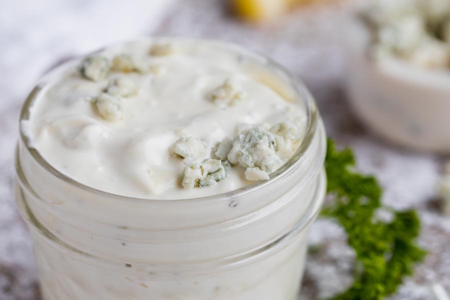 crumbled blue cheese on top of a container of dressing