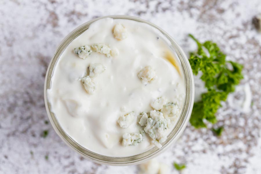 creamy blue cheese salad dressing in a jar with parsley next to it