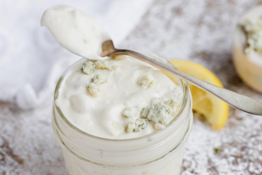 a spoon of dressing sitting on top of a jar of dressing