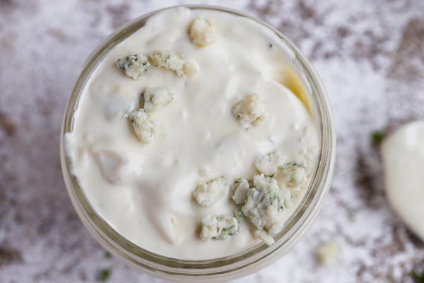 chunks of blue cheese on top of a container with dressing