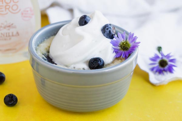whipped cream on top of a short cake with blueberries and purple flowers