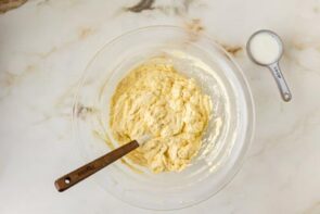 Keto cake batter partially mixed in a large bowl with a spatula, showing the ingredients just coming together.