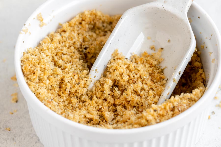 A scoop digging into fluffy keto bread crumbs in a bowl.