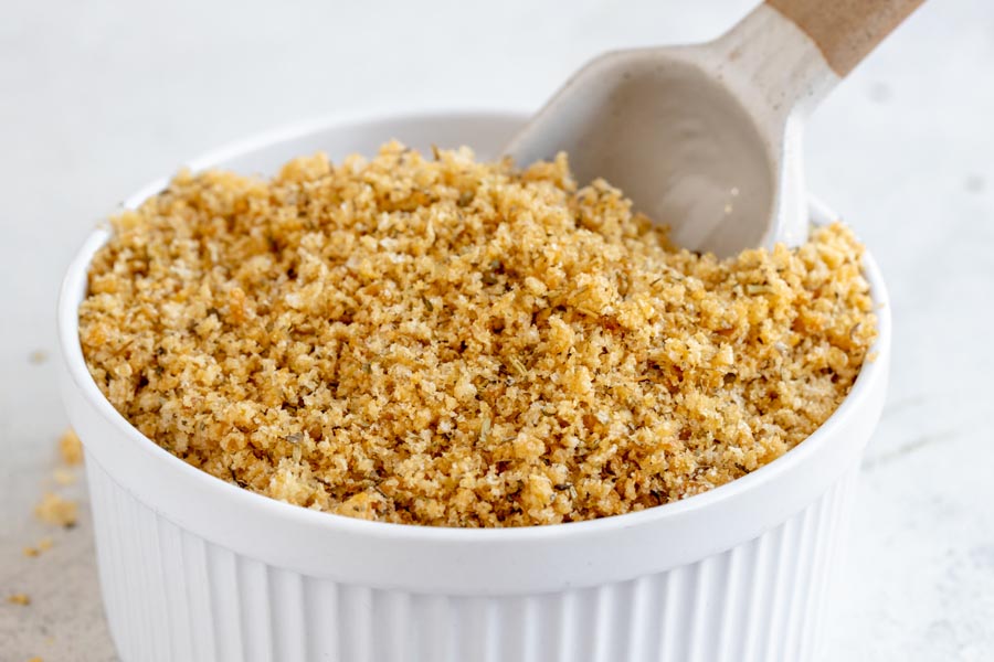 A large ramekin of bread crumbs with a scoop inside.